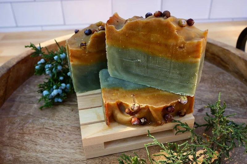 brown and green soap bars stacked on a wooden soap dish