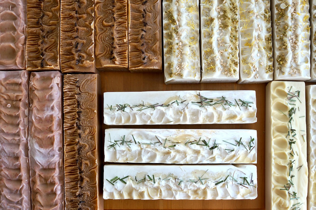 whole soap loaves lined up on a wooden table. 